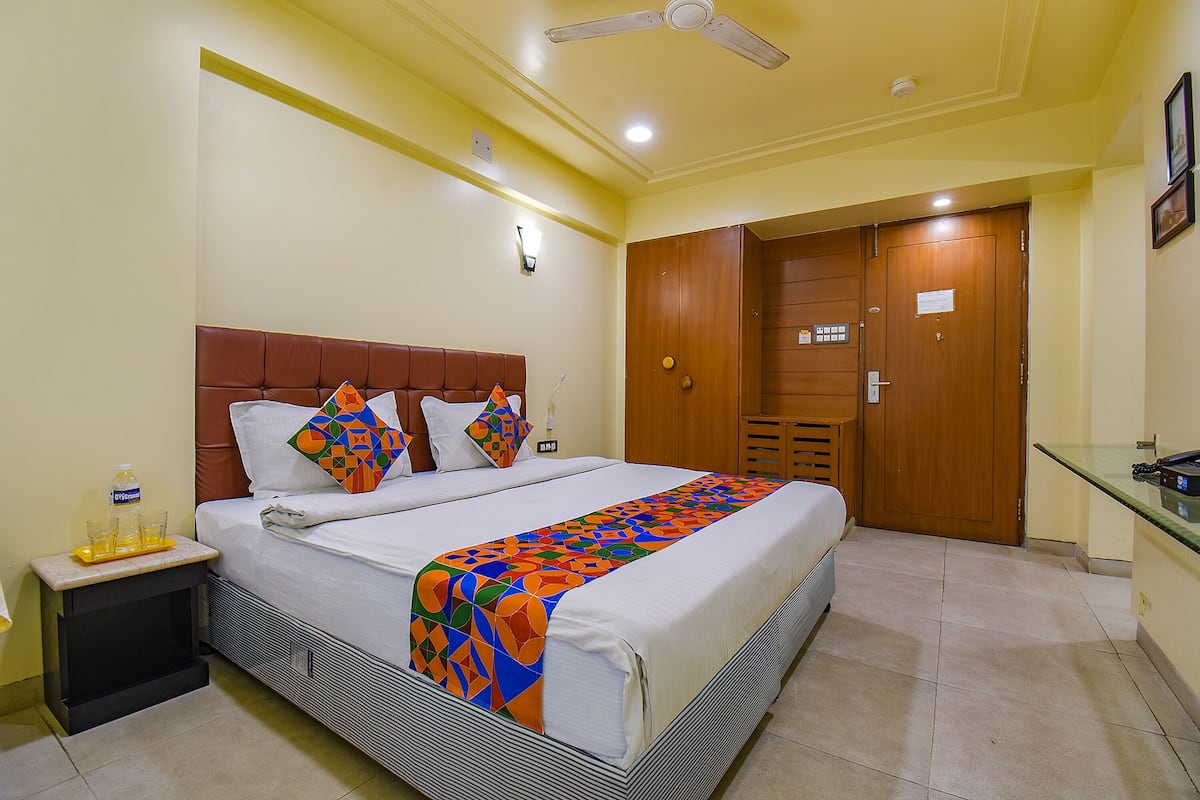A hotel room with a bed, bedside table, nightstand, and a wooden wardrobe.