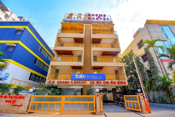 Um edifício com várias andares e varandas, com uma placa indicando 'S.R. Rooms & Hostel'.