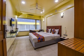 Una habitación de hotel con cama, mesita de noche y escritorio con silla.