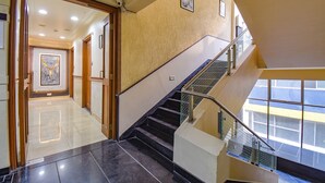 A modern hotel interior with a staircase, a hallway leading to a room, and a large window providing a view. - Fabhotel Sr Wakad (Paud)