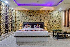 A hotel room with a bed, bedside tables, a chair, and a small table. - Fabhotel Gold Galaxy (Kanpur)