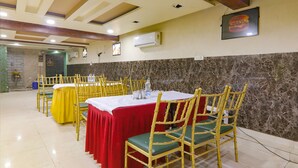 A conference room with multiple tables and chairs, air conditioning units, and a marble wall. - Fabhotel Gold Galaxy (Kanpur)