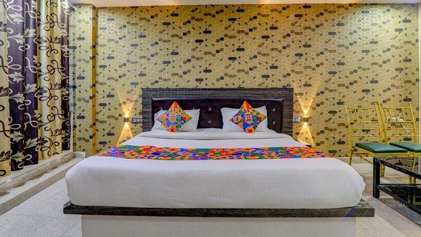 A hotel room with a large bed, patterned curtains, and a decorative wall. - Fabhotel Gold Galaxy (Kanpur)
