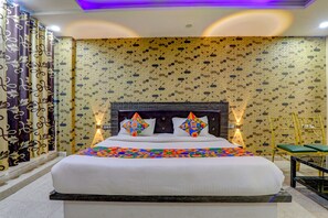 A hotel room with a large bed, patterned curtains, and a decorative wall. - (Kanpur)
