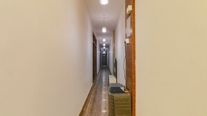 A narrow hallway with wooden flooring, a trash bin, and a light fixture. - Fabhotel Gold Galaxy (Kanpur)