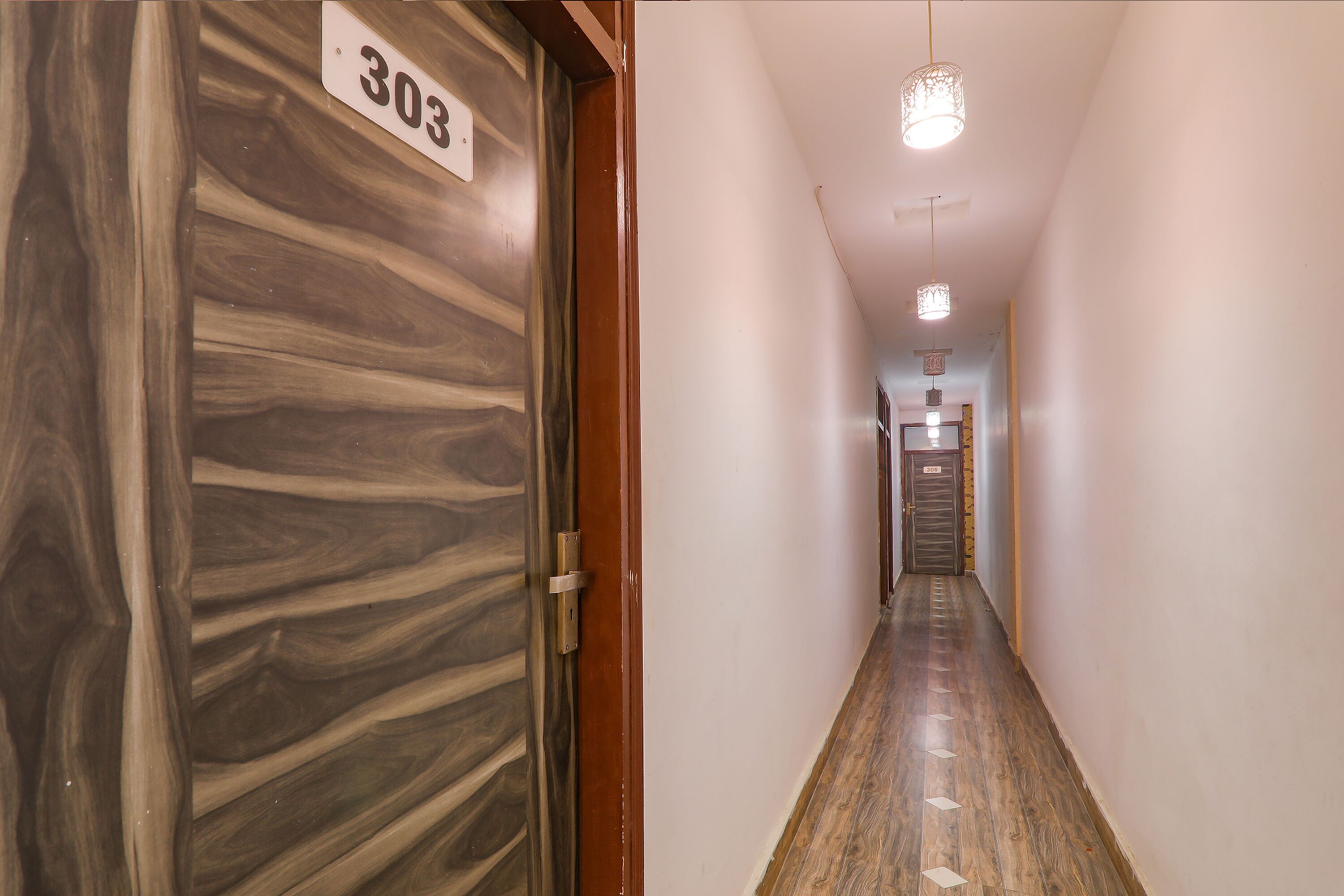 A hallway with a wooden door labeled "303" and a light fixture above.