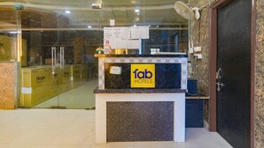 A hotel reception desk with a glass partition, a clock, and a G Pay sign. - Fabhotel Gold Galaxy (Kanpur)