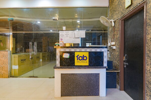 A hotel reception desk with a glass partition, a clock, and a G Pay sign.