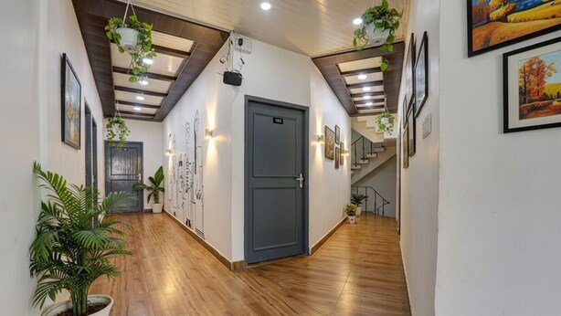 A hallway with wooden flooring, a grey door, and potted plants. - Fabhotel Super 3 Premium Ii (Kanpur)