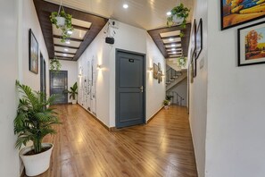 A hallway with wooden flooring, a grey door, and potted plants.