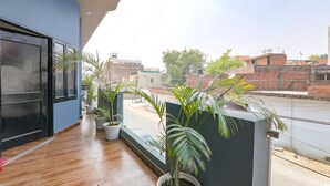A balcony with wooden flooring, potted plants, and a view of the cityscape. - Fabhotel Super 3 Premium Ii (Kanpur)