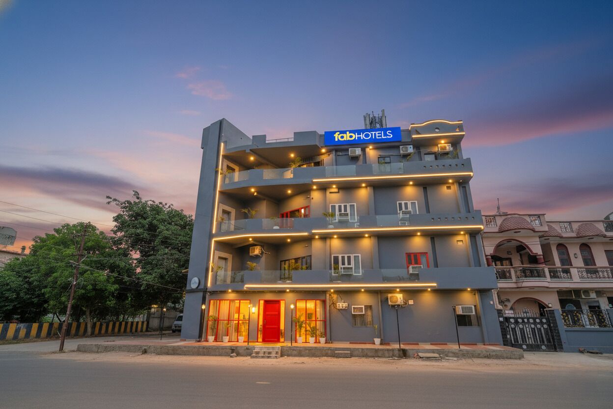 Un hotel de varios pisos con un letrero llamativo de 'fabHOTELS', balcones y una puerta de entrada roja.