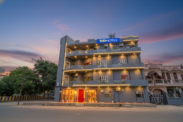 A multi-story hotel with a prominent 'fabHOTELS' sign, balconies, and a red entrance door.