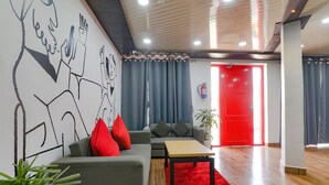 A modern living room with a grey sofa, red cushions, a wooden coffee table, and a red rug. - Fabhotel Super 3 Premium Ii (Kanpur)