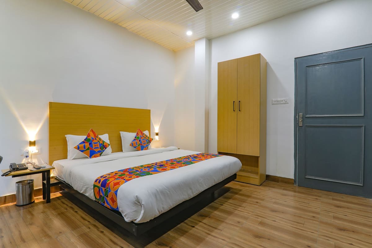 Une chambre d’hôtel comprenant un lit, une table de chevet, une lampe, une armoire et une porte.