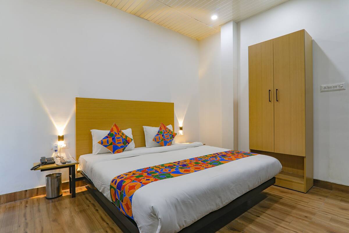 Une chambre d’hôtel comprenant un lit, une table de chevet, une lampe et une armoire.