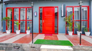 A building with a red door, multiple windows, and potted plants. - Fabhotel Super 3 Premium Ii (Kanpur)