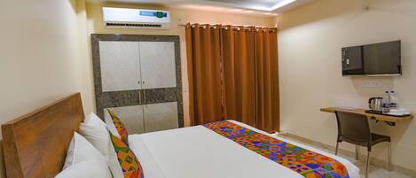 Une chambre d’hôtel équipée d’un lit, d’un bureau, d’une chaise, d’une télévision et d’un appareil de climatisation.