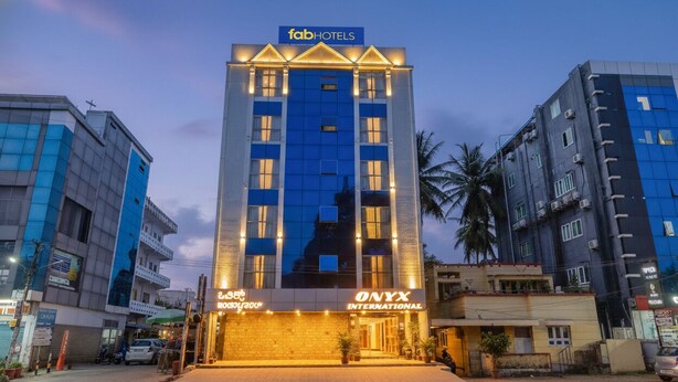 A tall hotel building with 'fab hotels' and 'NYX INTERNATIONAL' signage, featuring a modern facade and multiple windows. - FabHotel Cozzy Inn - Jayanagar (Bengaluru)