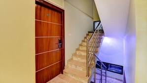 A wooden door with a number plate, a staircase with metal railings, and a window at the top of the stairs. - FabHotel Cozzy Inn - Jayanagar (Bengaluru)