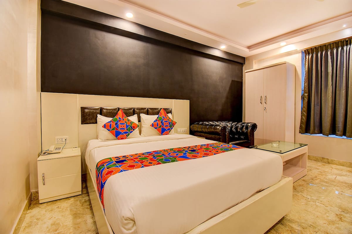 A hotel room with a large bed, a nightstand, a wardrobe, and a glass table.
