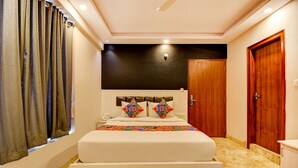 A bedroom with a bed, curtains, a wooden door, and a ceiling light. - FabHotel Cozzy Inn - Jayanagar (Bengaluru)