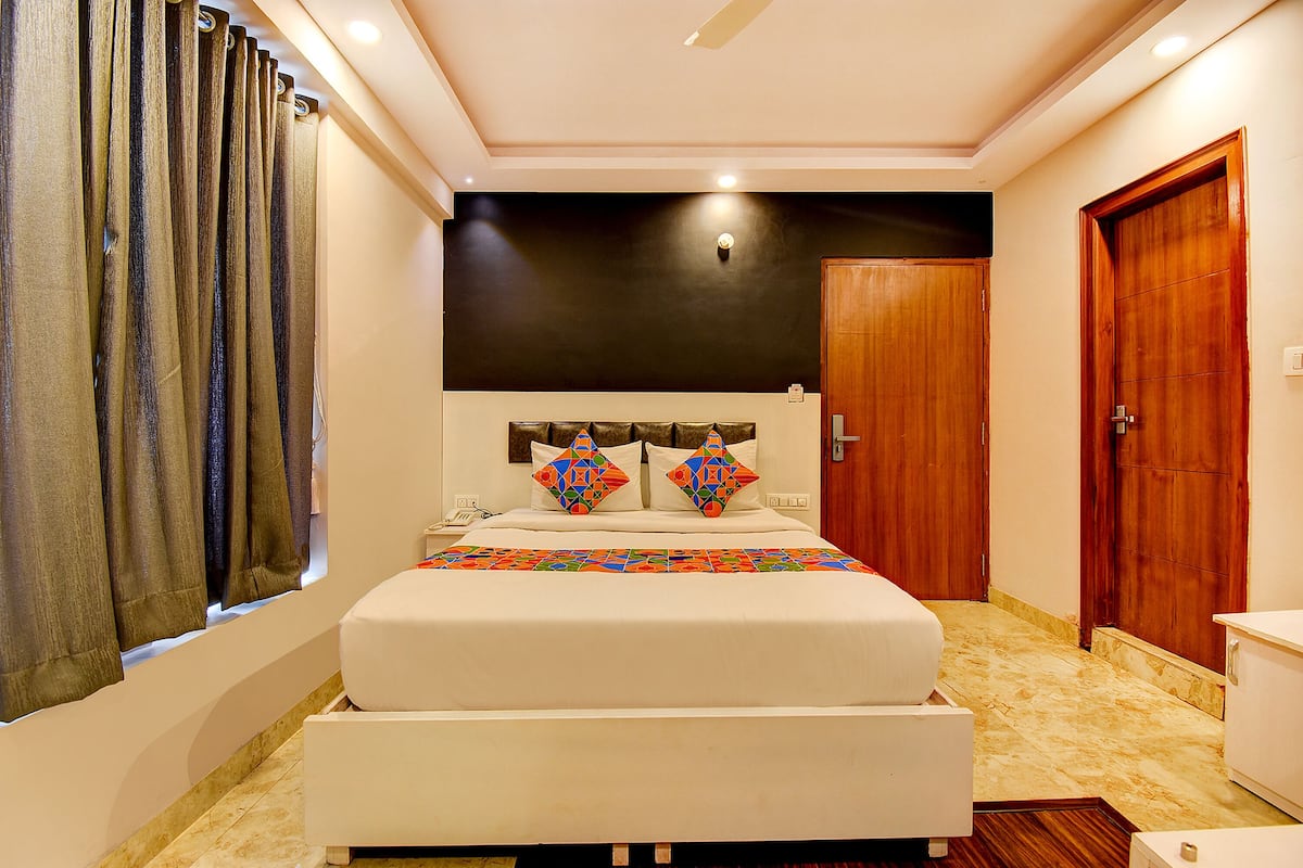 A bedroom with a bed, curtains, a wooden door, and a ceiling light.