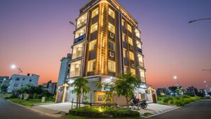 A multi-story hotel with a modern design, featuring balconies and air conditioning units on the exterior.