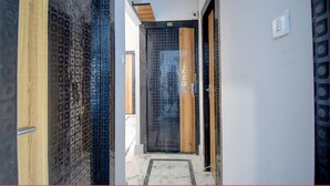 A hallway with patterned doors, a tiled floor, and a visible door number. - FabHotel Amar Raj Villa (Barasat)