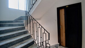 A staircase with marble steps and black metal railings, leading to a wooden door with a number plate. - FabHotel Amar Raj Villa (Barasat)