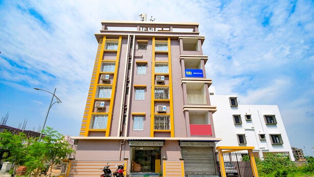 A multi-story building with a yellow and brown facade, a visible entrance, and a gated parking area with motorcycles.