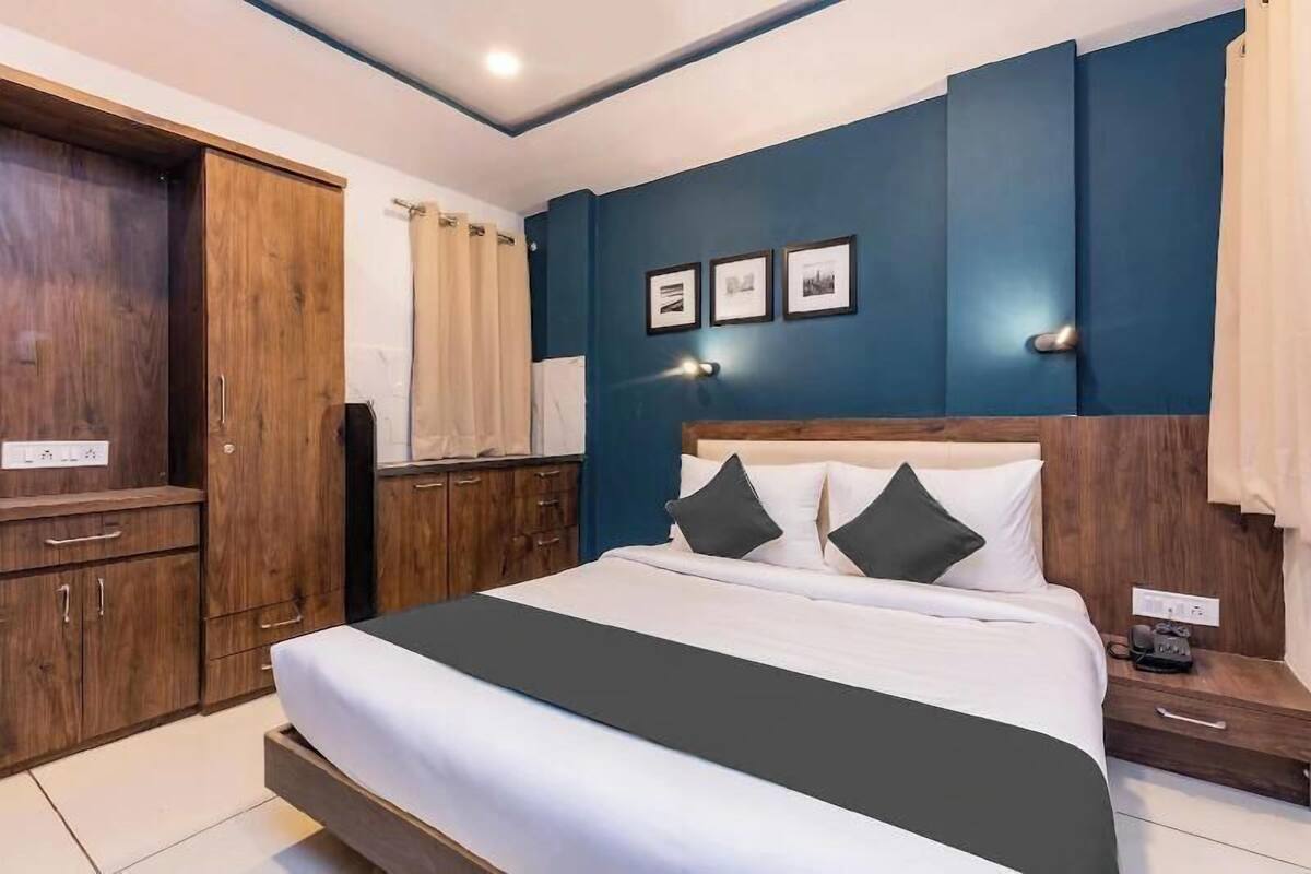 A bedroom with a bed, wooden wardrobe, and a nightstand.