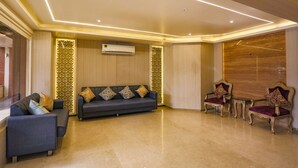 A modern lobby with a sofa, two armchairs, and a patterned wall. - Fabhotel Surya (Bhopal)