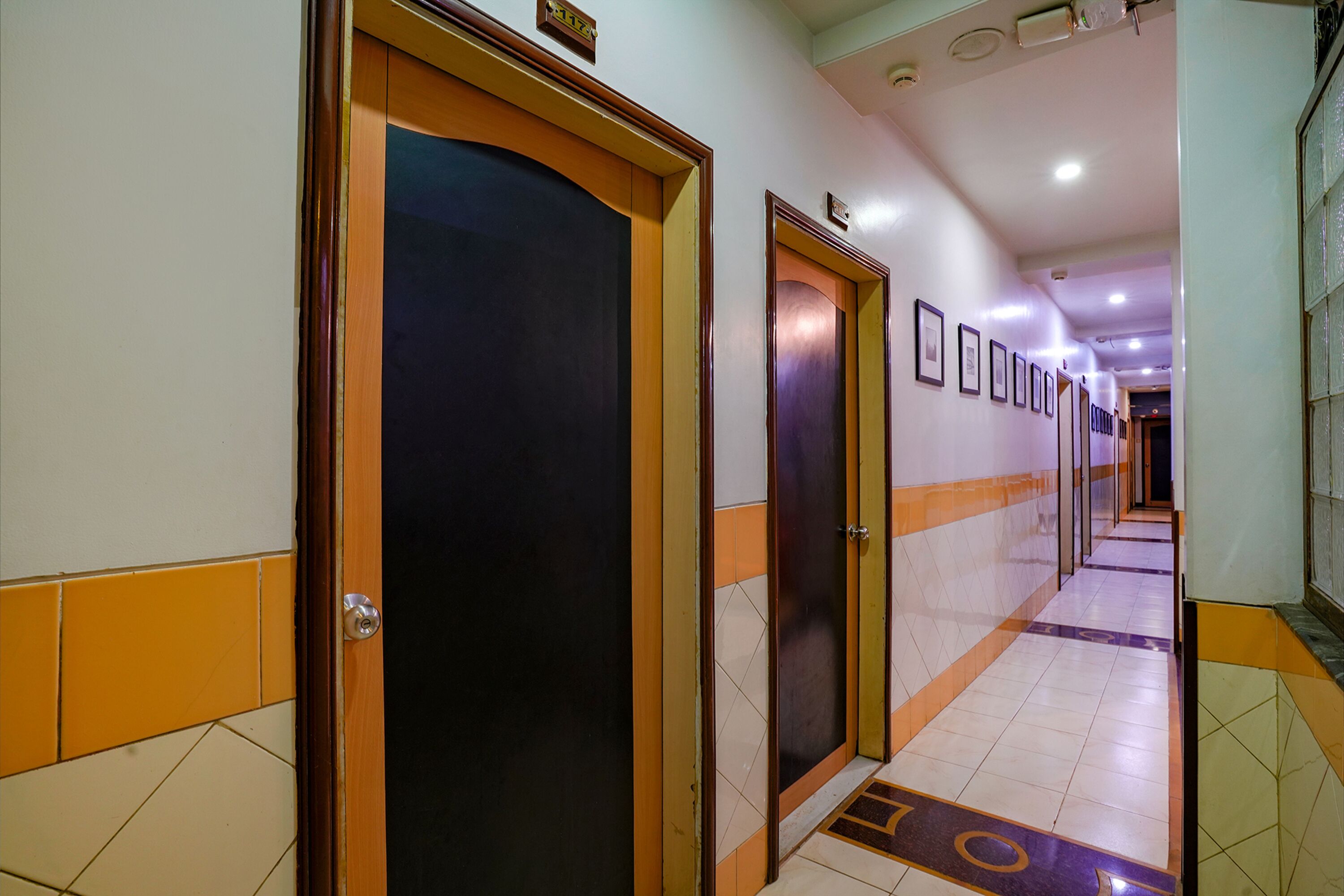 Un couloir avec des portes, un sol carrelé et un plafond doté d’un éclairage encastré.