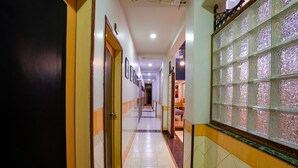 Un couloir doté d’un sol carrelé, de portes et d’un panneau de verre décoratif sur le côté droit.
