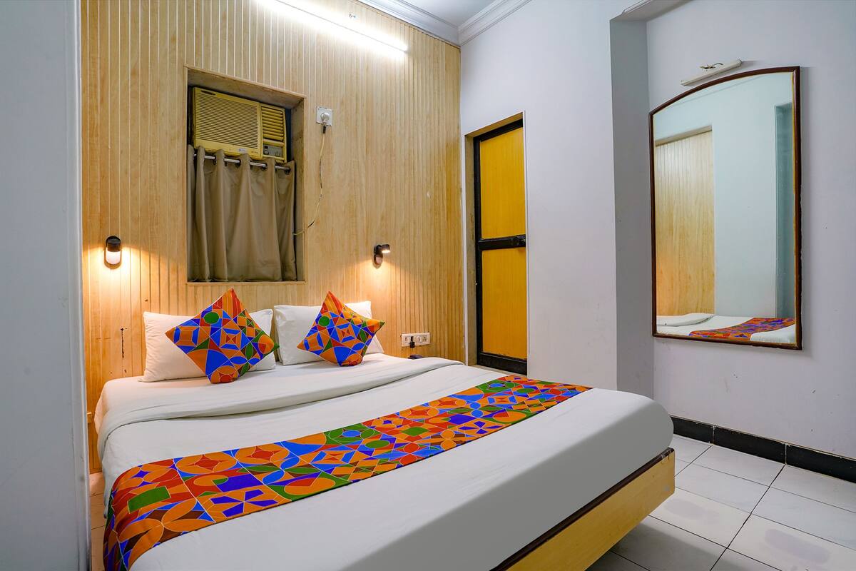 A neatly made bed with a colorful geometric-patterned bedspread and two decorative pillows.