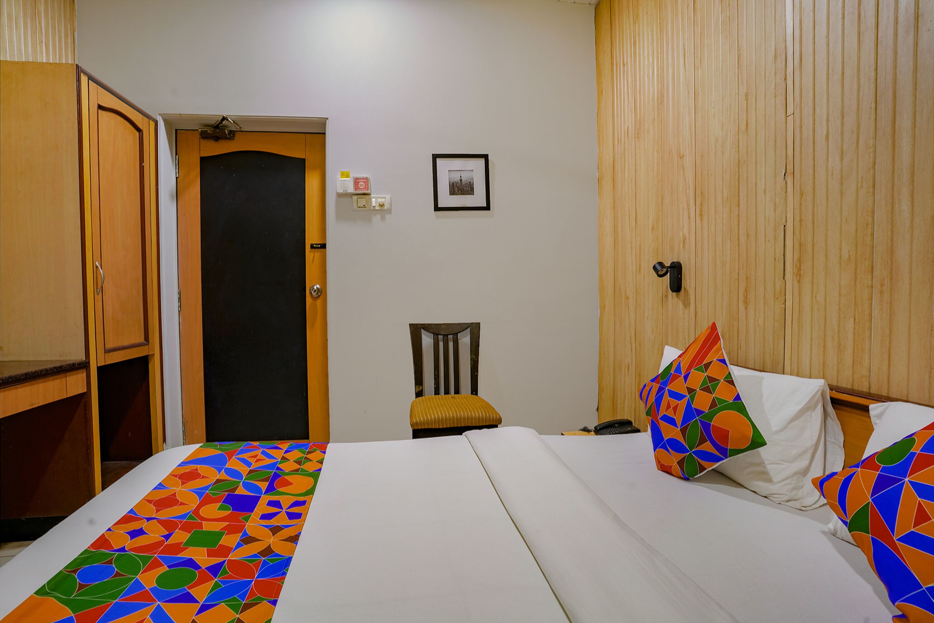 Una habitació d'hotel amb un llit, una cadira, un armari i una porta.