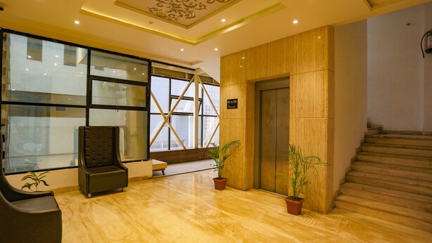 A lobby with a wooden floor, a black chair, a wooden wall, and a staircase. - Fabhotel Sun Park (Bhopal)
