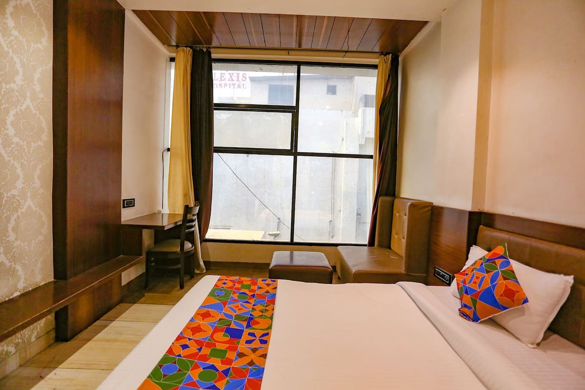 Habitación de hotel con cama, escritorio, silla y ventana con vista a un edificio.