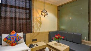 A hotel room with a bed, a sofa, a small table with a vase of flowers, and a hanging light fixture. - Fabhotel Sun Park (Bhopal)