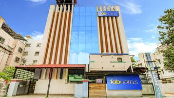 A tall hotel with a modern facade, a prominent sign reading "fabHOTELS", and a gated entrance.