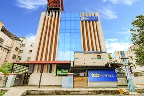 A tall hotel with a modern facade, a prominent sign reading "fabHOTELS", and a gated entrance.