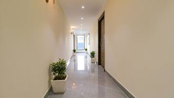 A hallway with a marble floor, potted plants, and a door at the end.