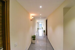 A hallway with a tiled floor, potted plants, and recessed lighting. - Fabhotel Prime K9 Regency (Jalandhar)