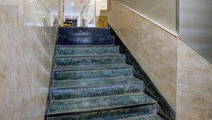 A marble staircase with a handrail, leading to a lobby area with a sign that reads "HOTEL". - Veera Residency (Mumbai)