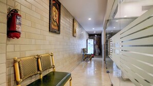 A hallway with a bench, a fire extinguisher, and framed artwork on the walls. - Veera Residency (Mumbai)