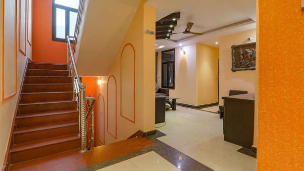 Een hotelhal met een trap, een receptiebalie en een plafondventilator.