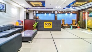 Un espace d’accueil d’hôtel au design moderne, comprenant un comptoir d’accueil, un coin salon et une grande fenêtre équipée de stores.