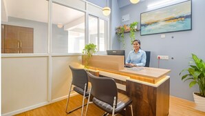 A reception desk with two chairs, a computer, and a plant. - Via Corner Courtyard (Hyderabad)