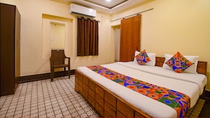 A hotel room with a bed, a chair, a wardrobe, and an air conditioning unit. - FabHotel Golden Imperial (Kolkata)